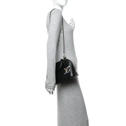 Black handbag on arm with top handle, gold zipper hardware, and colorful LV motif