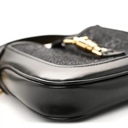 Close-up of black hobo bag top edge with gold chain strap and textured lining.