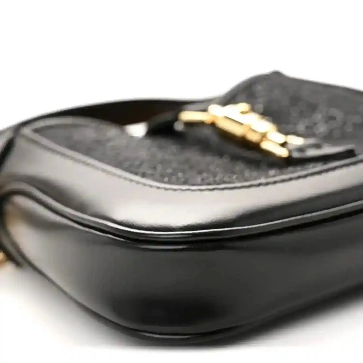 Close-up of black hobo bag top edge with gold chain strap and textured lining.