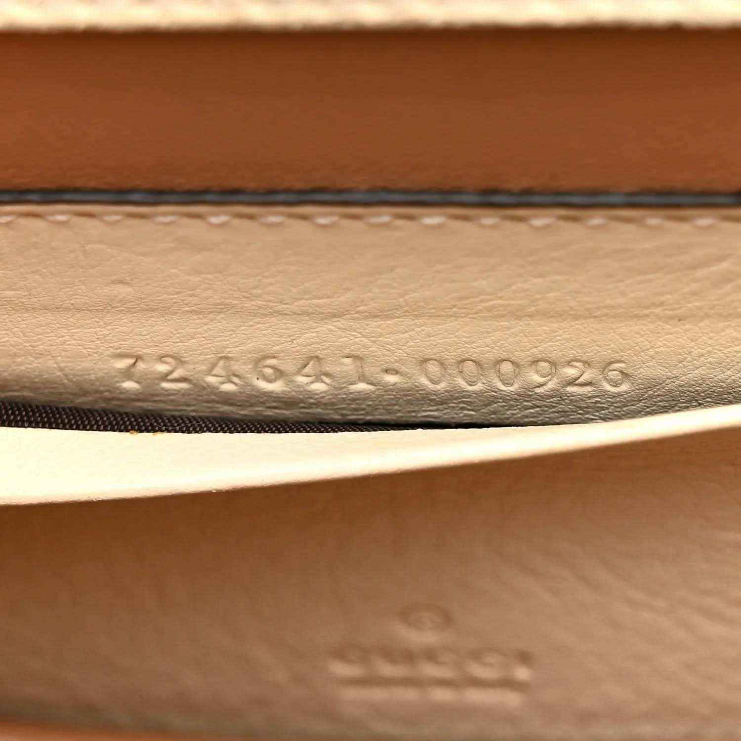 Stamped serial number on inside leather panel of a white mini handbag