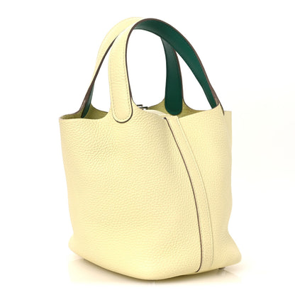 Two-tone leather handbag with yellow exterior and green handle accent, front corner seam.