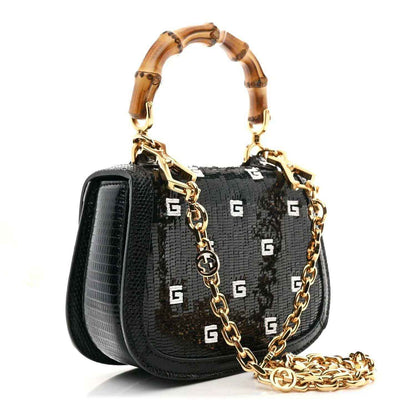 Black mini chain bag with gold chain strap and bamboo-style handles, front logo pattern