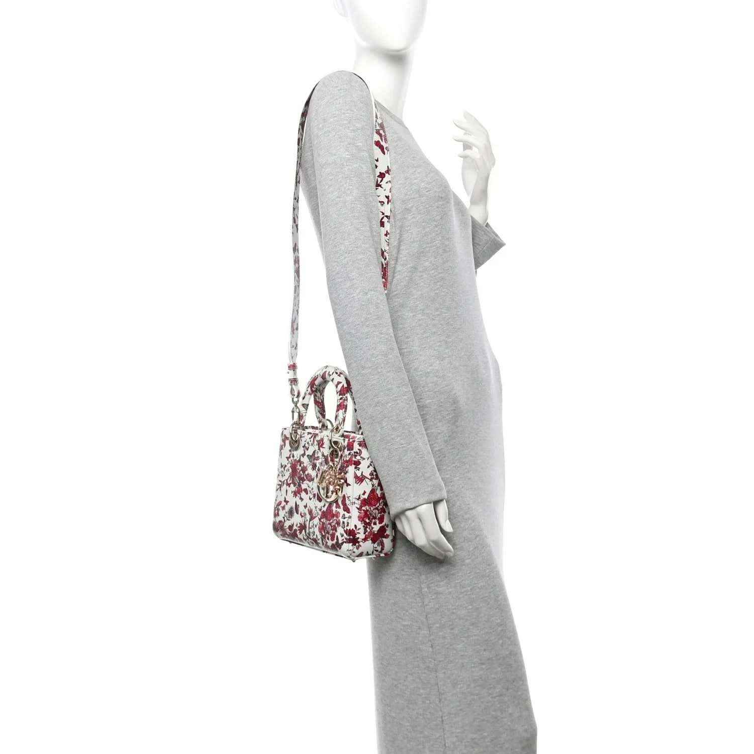 Small floral handbag shown from side with white body, red print, and long shoulder strap