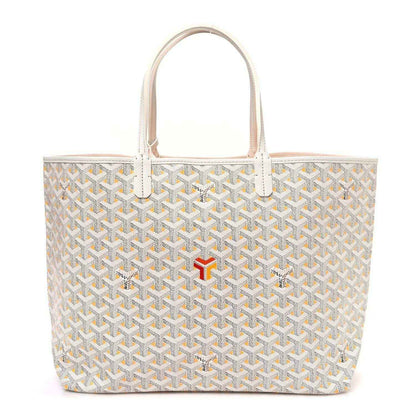 White tote bag with yellow Goyardine pattern, leather handles, and red logo accent at front