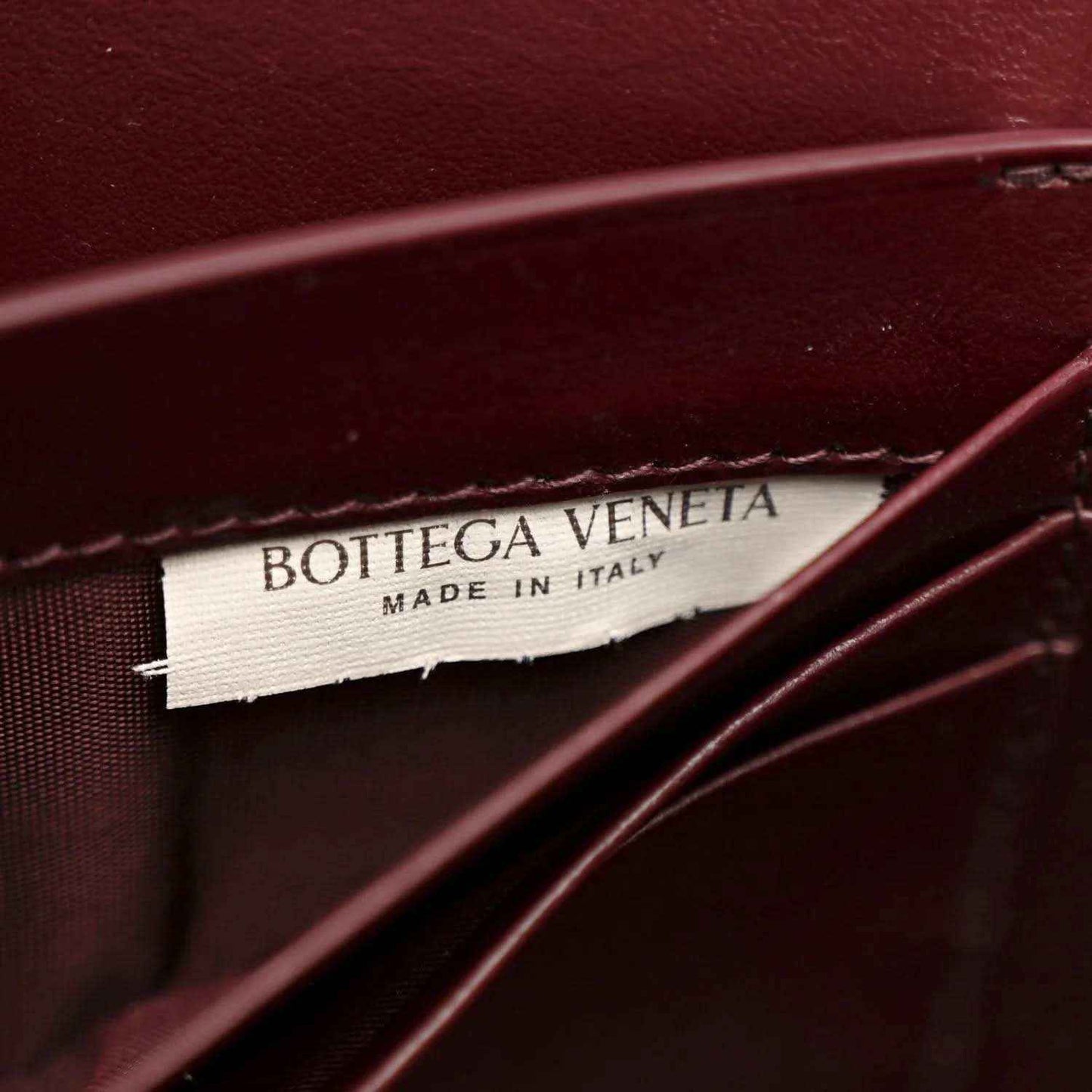 Bottega Veneta leather clutch with stitched logo label and burgundy interior panel