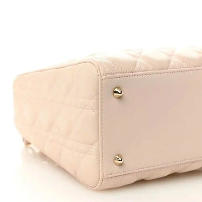 Powder pink quilted handbag side with gold-tone snap studs and curved corner.