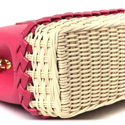 Magenta mini handbag with woven rattan side panels and pink leather straps, close-up