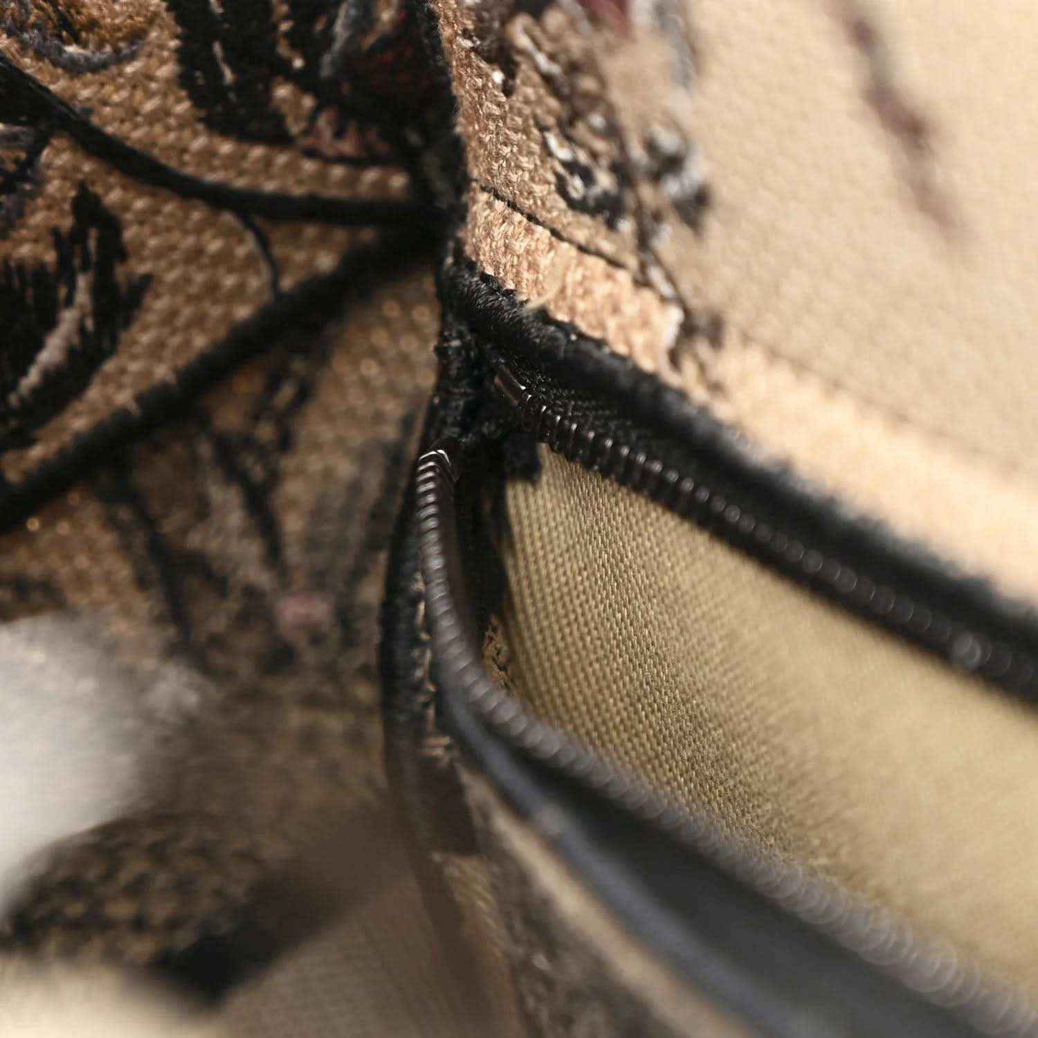 Embroidered canvas bag with black zipper trim and interior lining detail