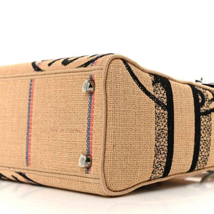 Jute canvas bag end panel with striped embroidery, silver studs, woven texture.