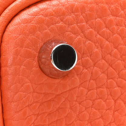 Orange pebbled leather handbag close-up of round metal lock plate