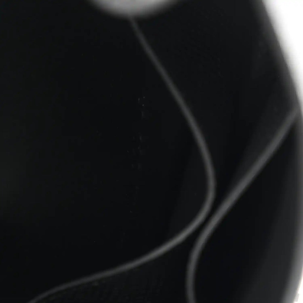 Black leather wallet corner with curved seam and edge stitching.