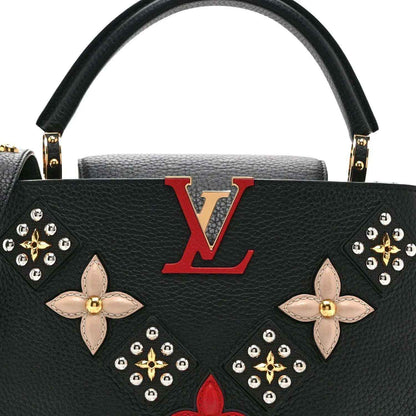 Black Louis Vuitton handbag front with red LV emblem and floral butterfly embellishments