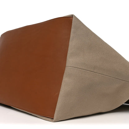 Beige canvas tote bag corner with brown leather base panel and seam stitching
