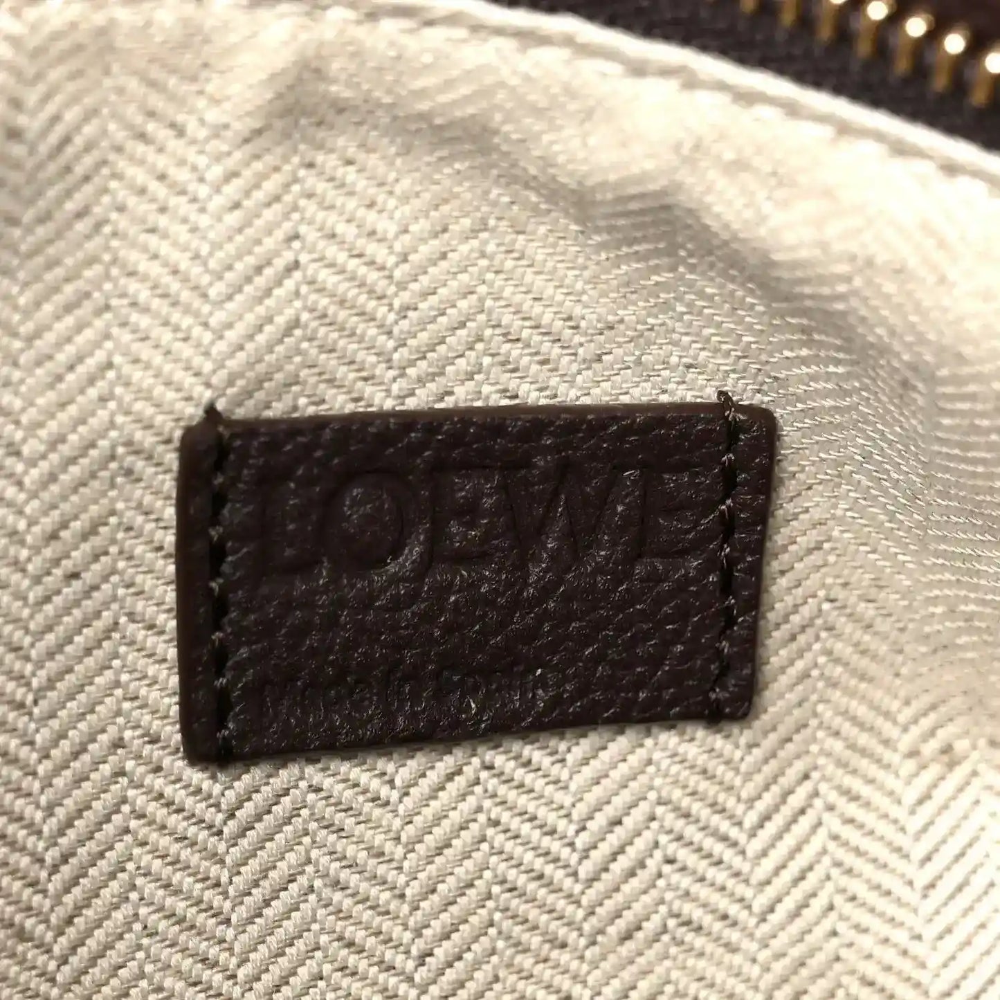 Leather interior patch label reading “LOEWE” on textured light-beige lining