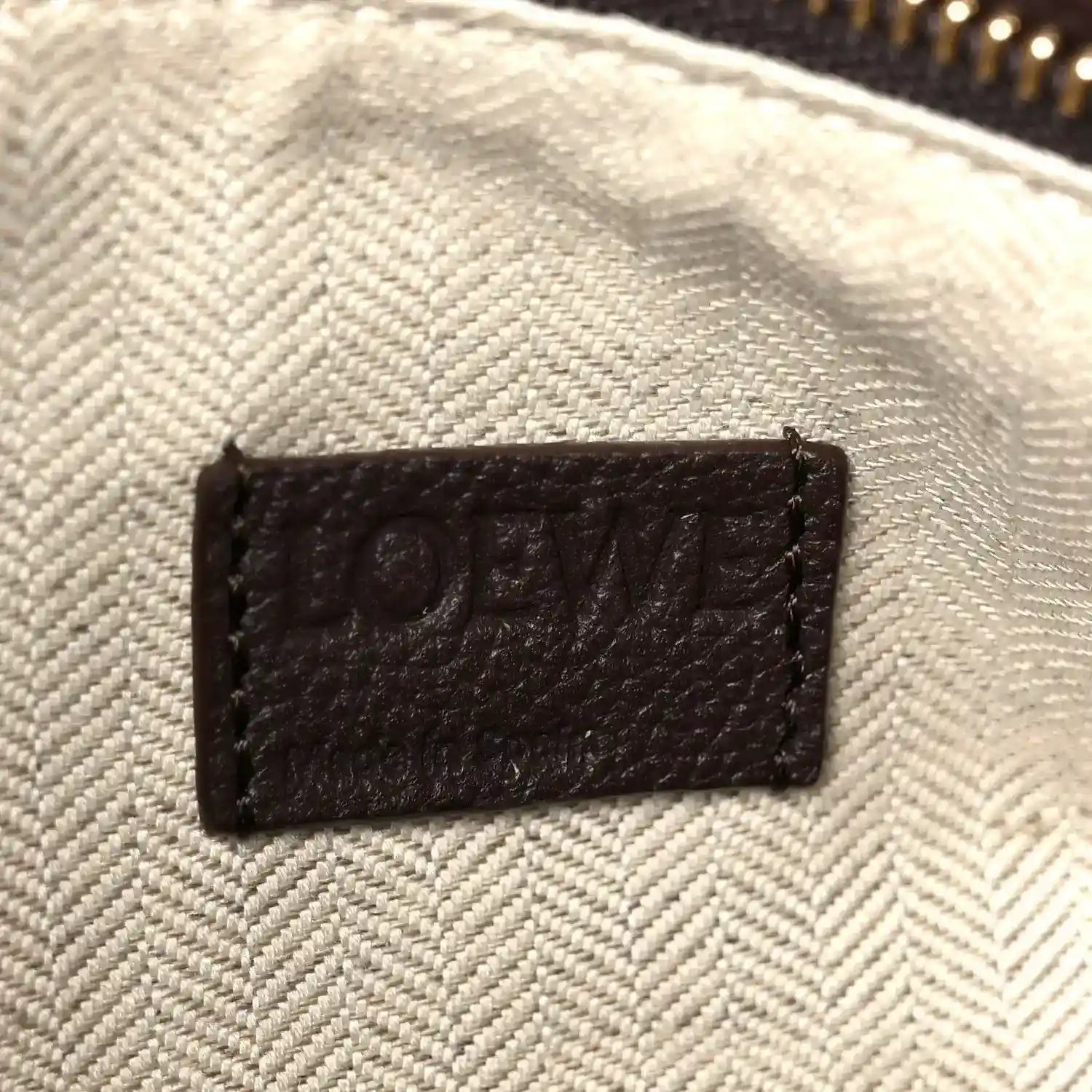 Leather interior patch label reading “LOEWE” on textured light-beige lining