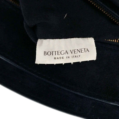 Black handbag with white fabric care label reading Bottega Veneta made in Italy