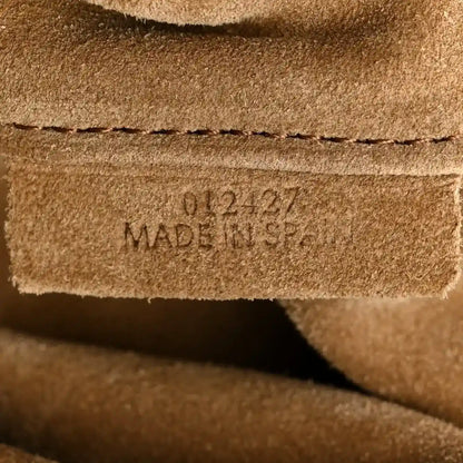 Stamped leather text reading MADE IN SPAIN on a light tan panel