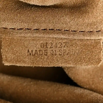Stamped leather text reading MADE IN SPAIN on a light tan panel