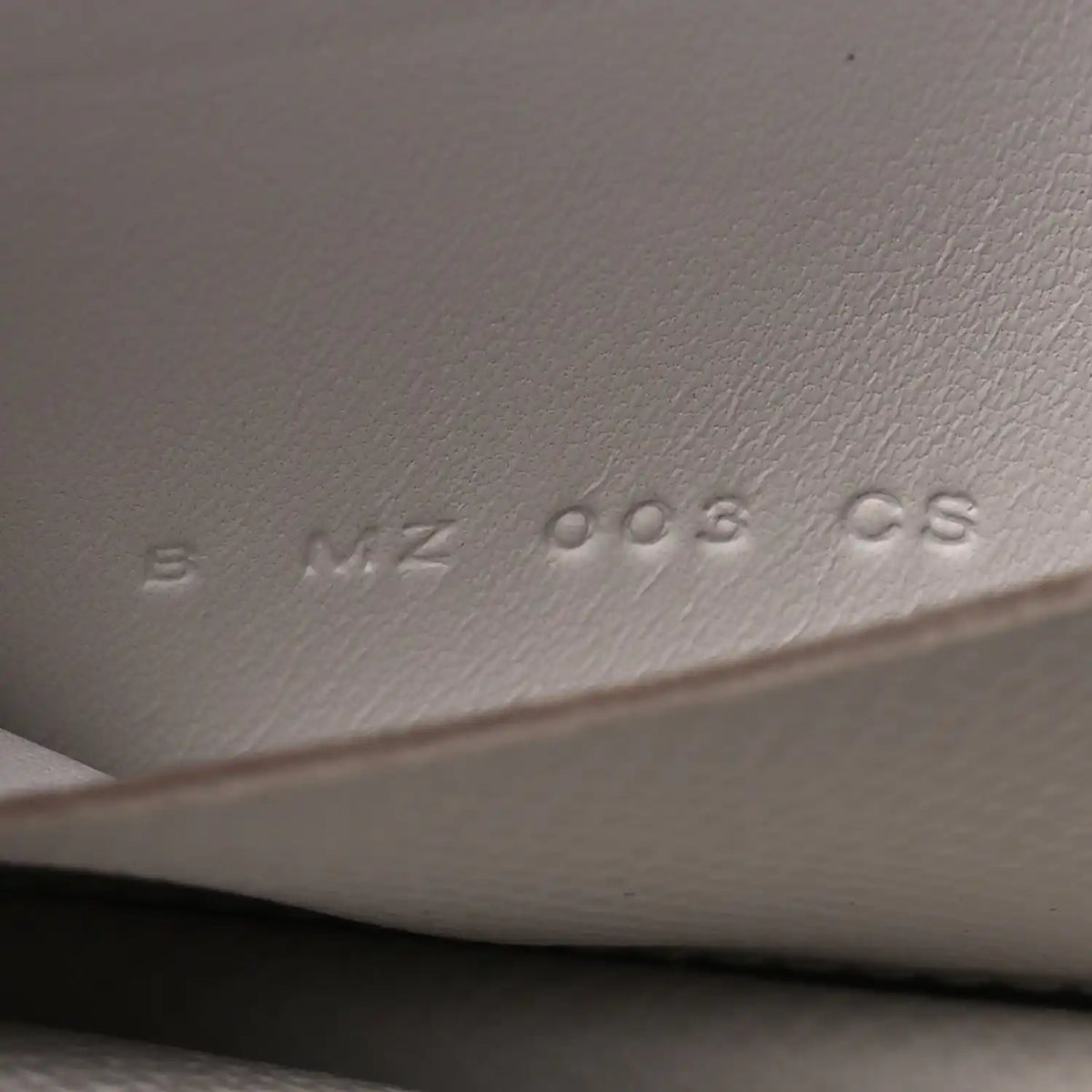 Embossed serial/markings on pale gray leather interior surface