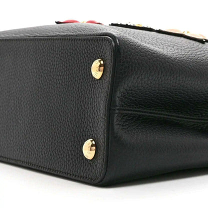 Black Louis Vuitton handbag side with gold stud accents and pebbled leather finish