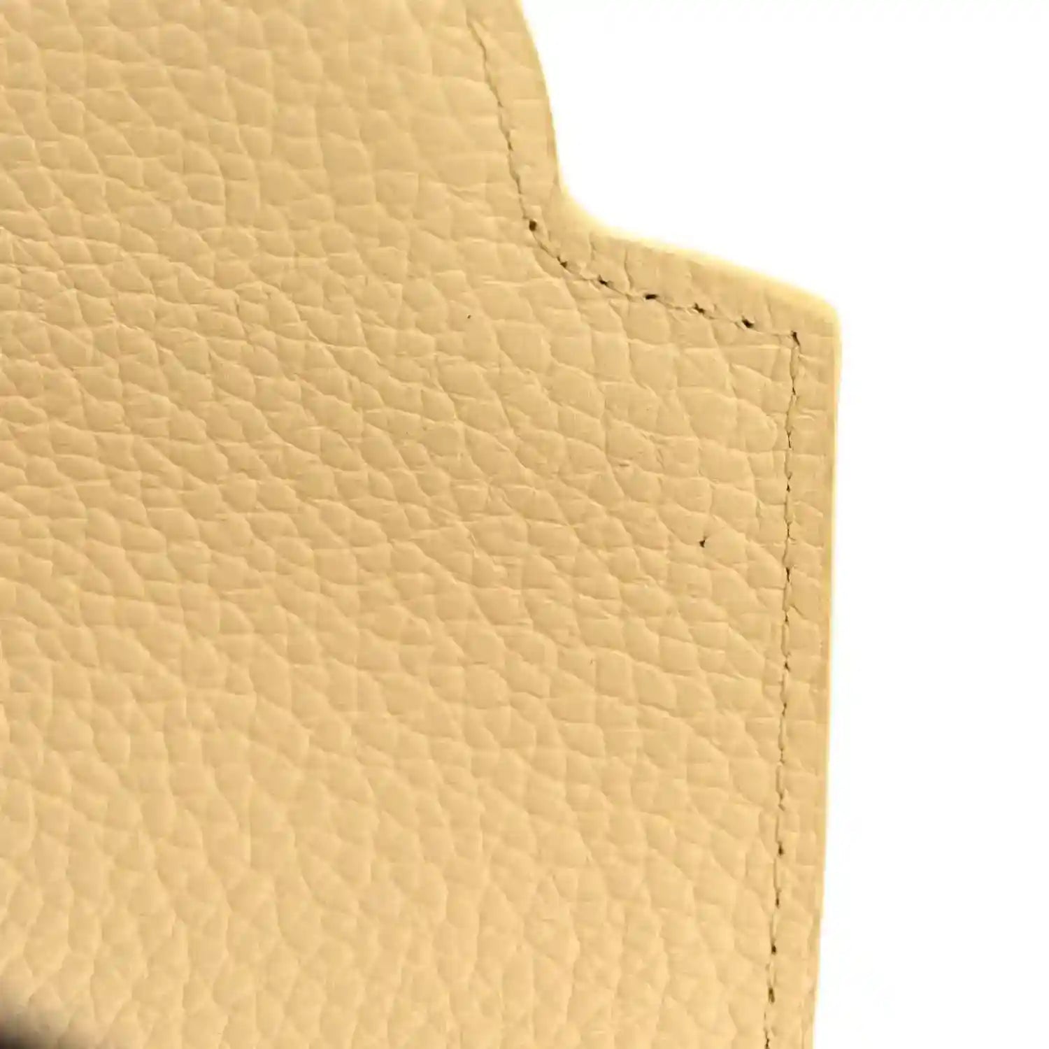 Cream pebbled leather handbag panel with fine texture and stitched edge.