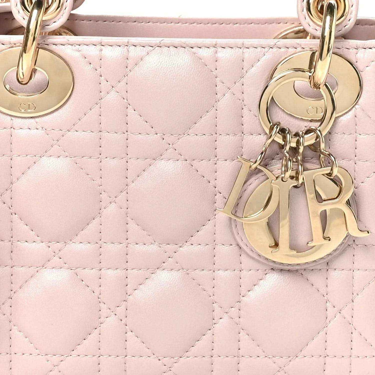 Mini Lady Dior handbag close-up: rose pink diamond Cannage quilting and gold hardware charms