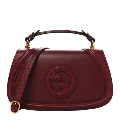 Maroon handbag with gold accents on a white background