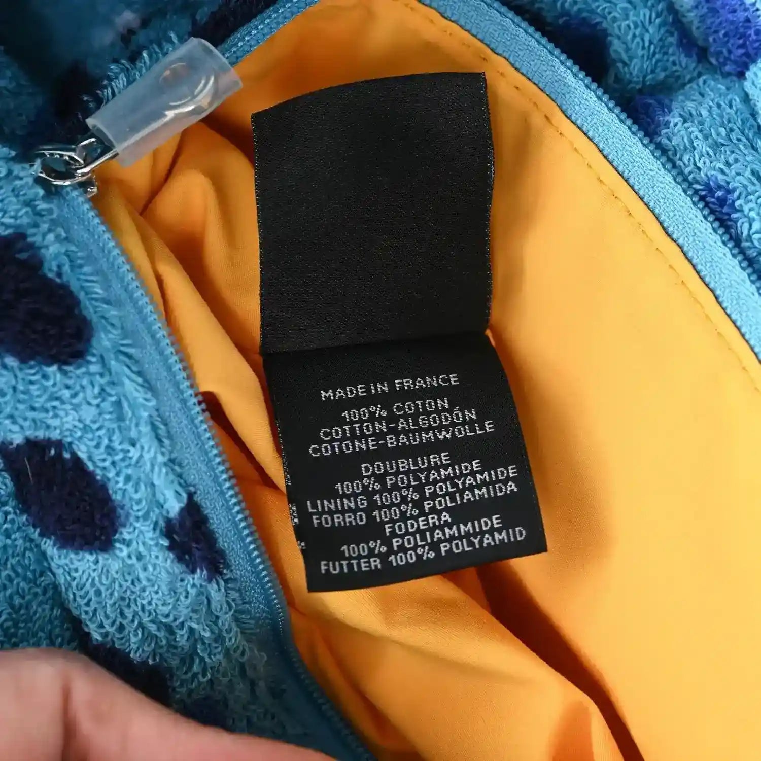 Orange-lined tote with fabric care label and zipper pull on turquoise terry edge.
