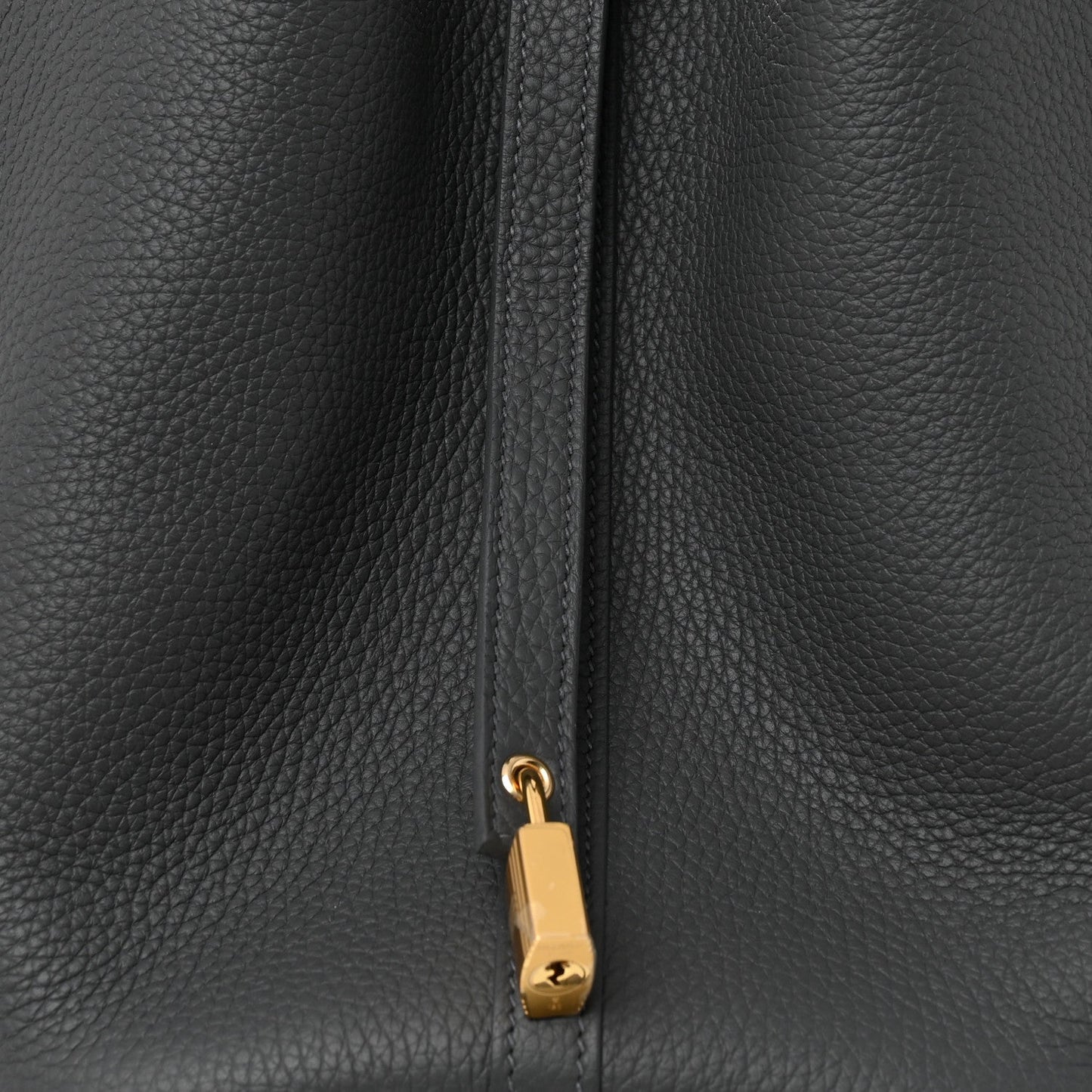 Close-up of dark gray leather zipper pull with gold-toned lock charm