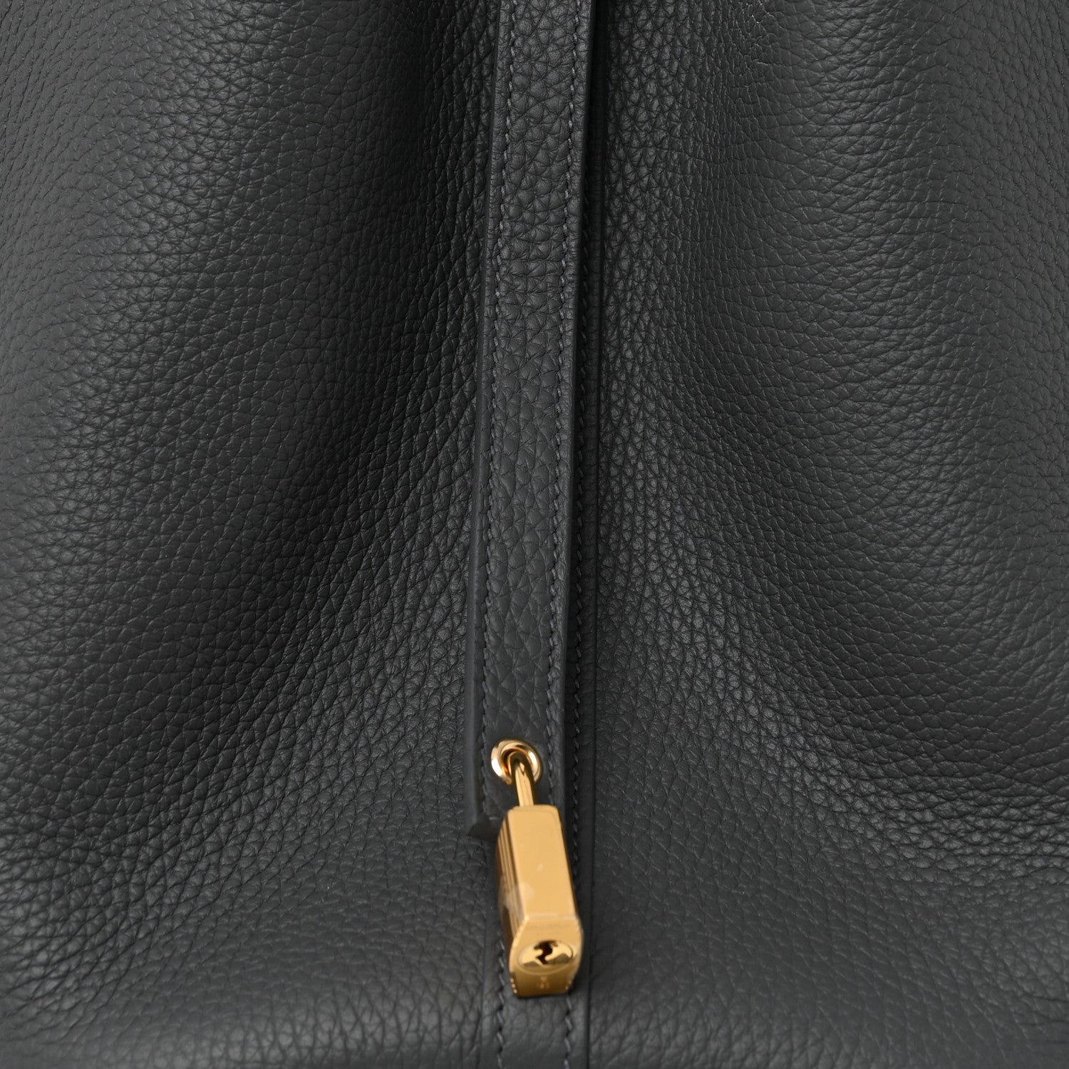 Close-up of dark gray leather zipper pull with gold-toned lock charm