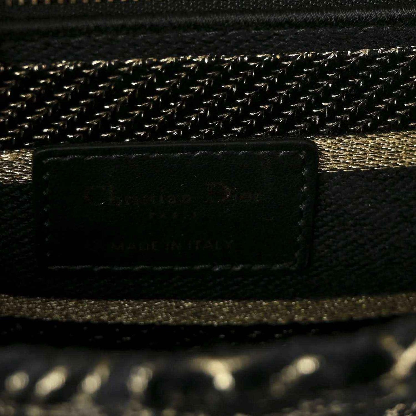 Close-up of handbag interior pocket and gold chain trim on black fabric