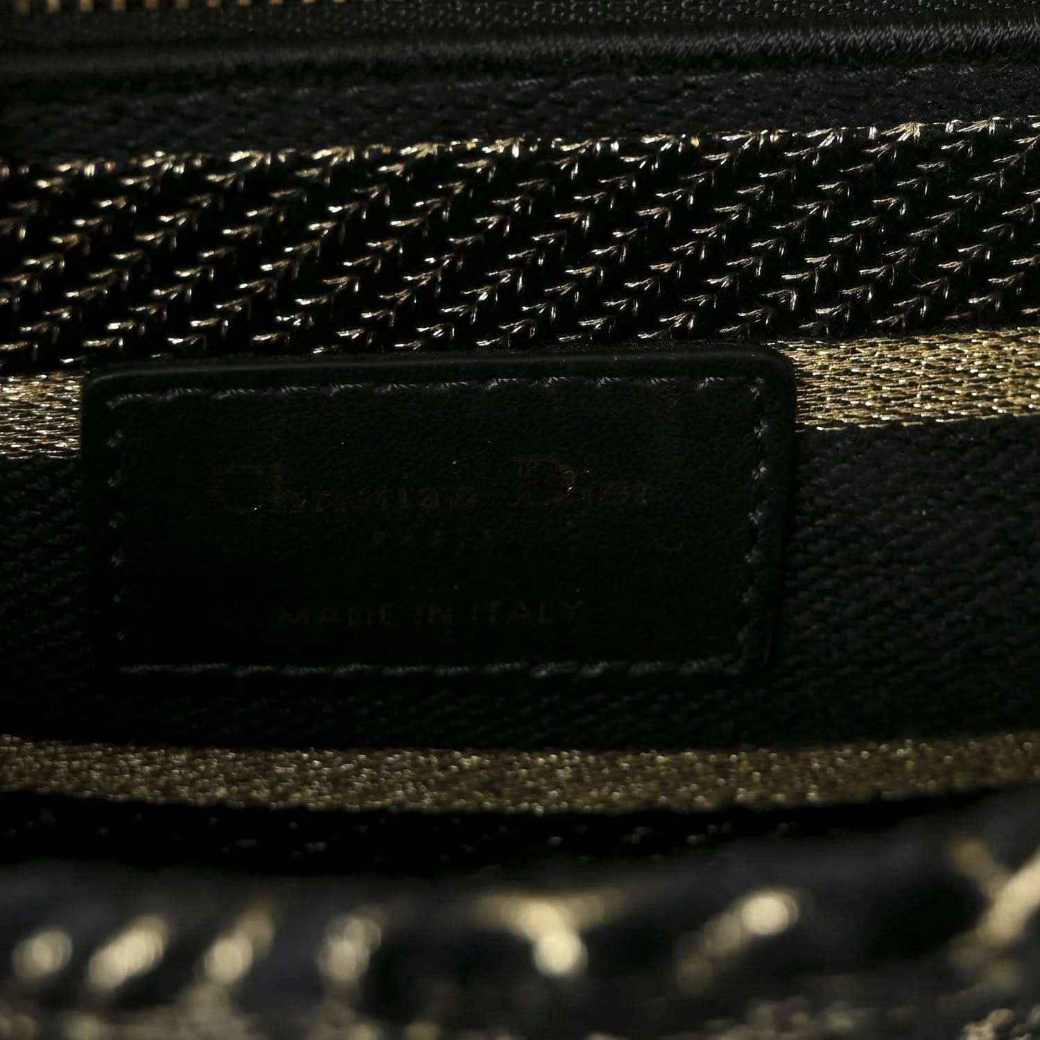 Close-up of handbag interior pocket and gold chain trim on black fabric