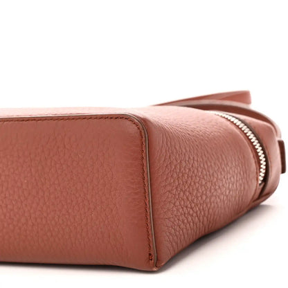 Side close-up of grained calfskin pouch with zipper edge and rounded base