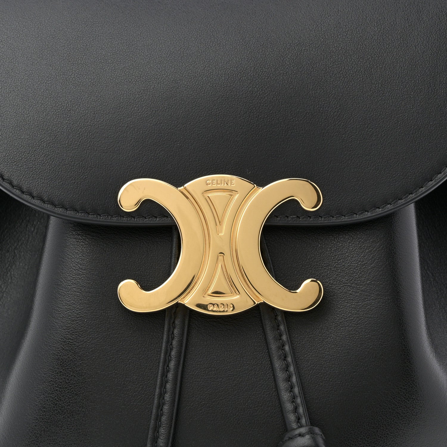 Celine Triomphe calfskin Bonnie backpack close-up of gold logo medallion and stitching.