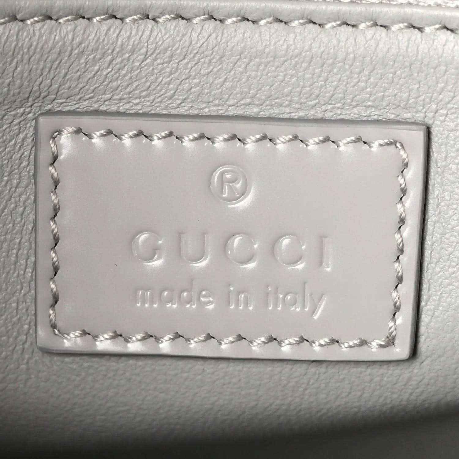 Light grey leather bag label with embossed Gucci and “Made in Italy” text