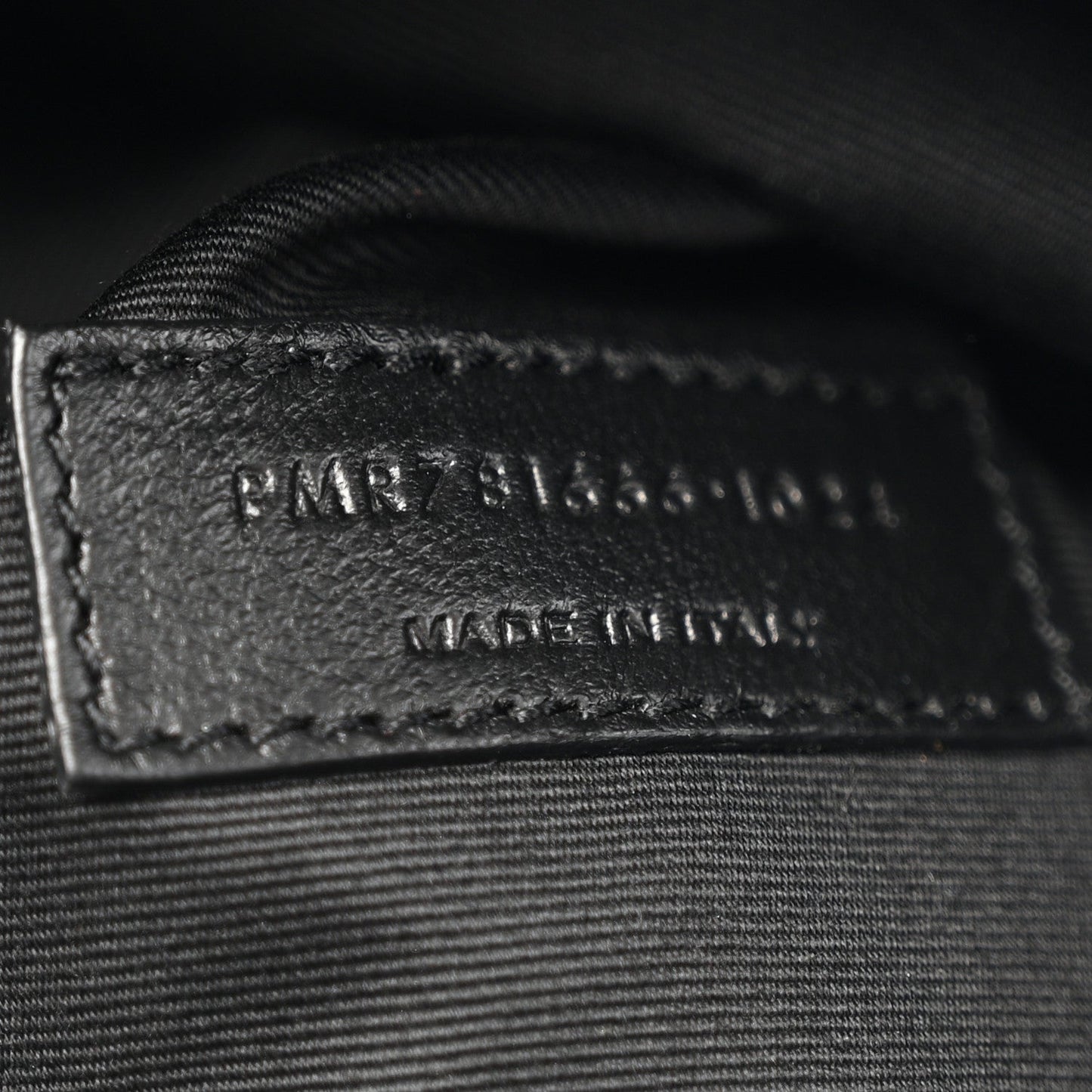 Black leather label with embossed branding and serial text on inner panel