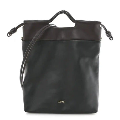 Black leather tote bag with top handles and side drawstring details.