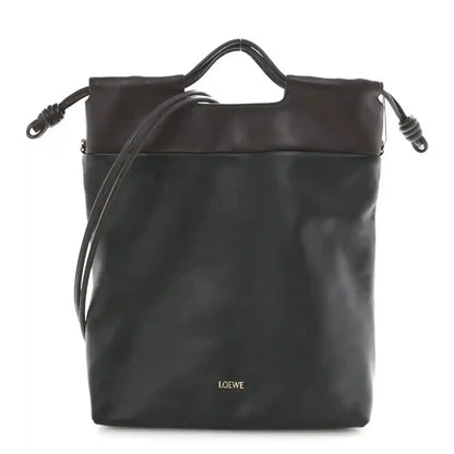 Black leather tote bag with top handles and side drawstring details.