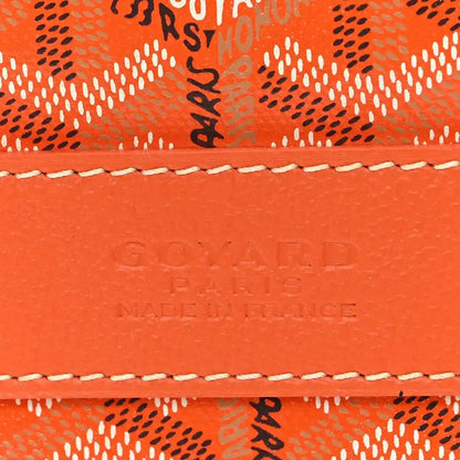 Embossed branding on orange leather trim of sports bag.