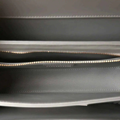 Light grey interior lining of a small shoulder bag with stitched edge and zipper track