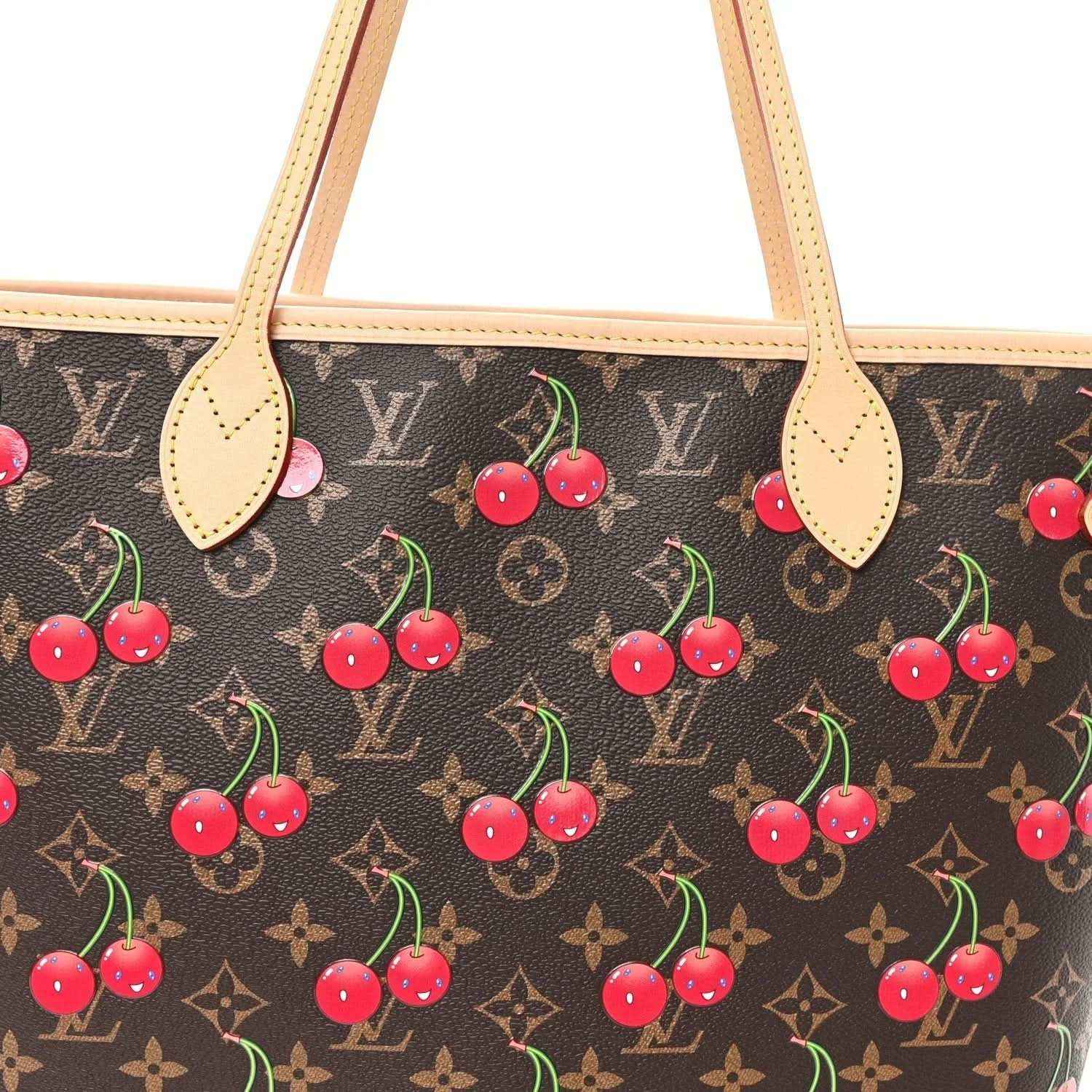 Close-up of cherry-printed monogram fabric with tan leather handle tabs.