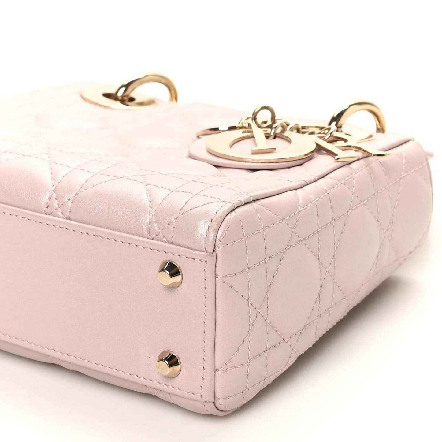 Mini Lady Dior handbag close-up with rose pink quilting, gold hardware, and top handle detail