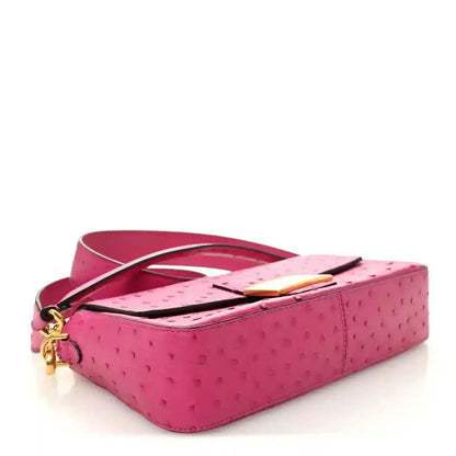 Pink ostrich leather baguette handbag with top handle, gold clasp, and crossbody strap