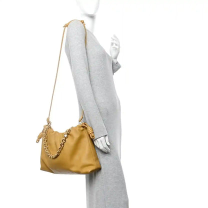Tan leather mini clutch with long chain strap and drawstring closure, on model