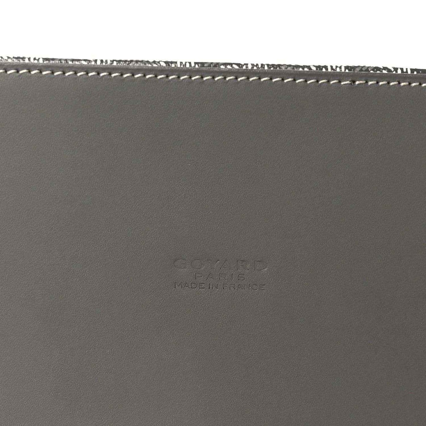 Grey leather handbag base with white stitching and subtle embossed maker text.