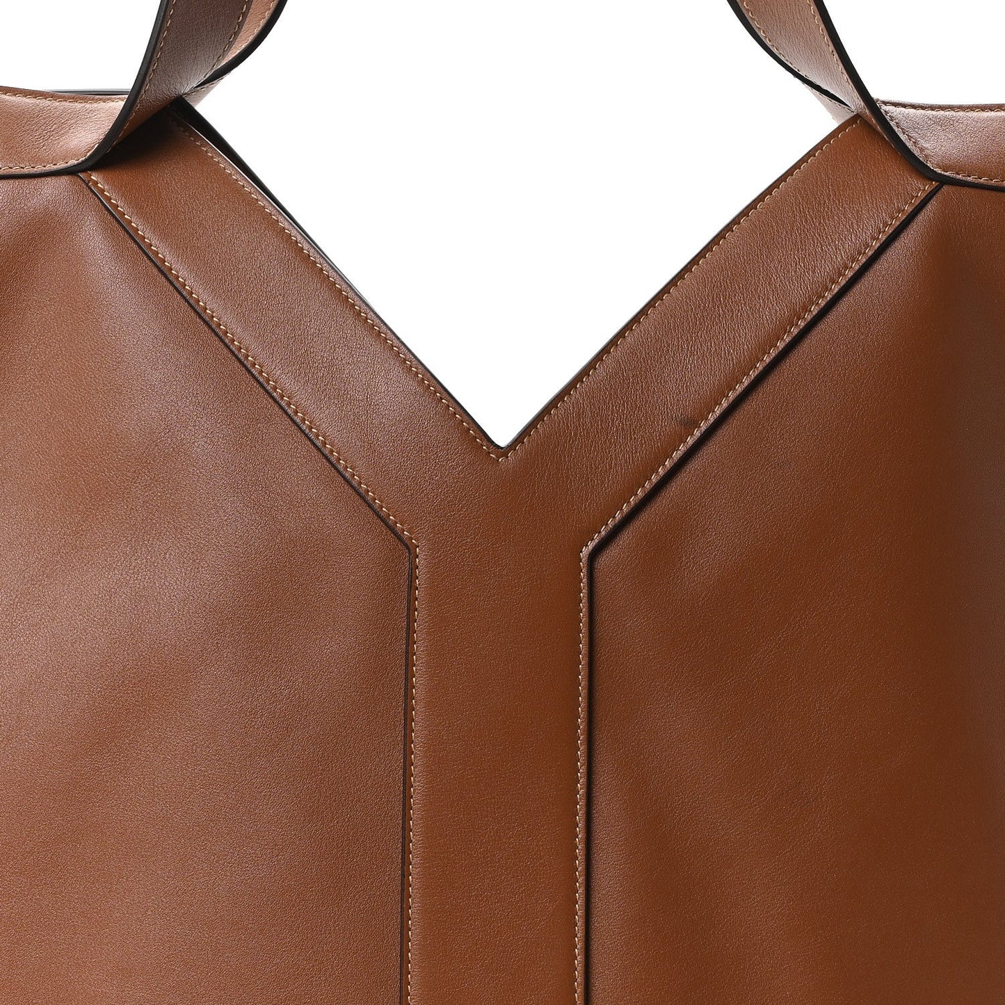 Close-up of tan-brown calfskin tote front seam and strap attachment at the V panel