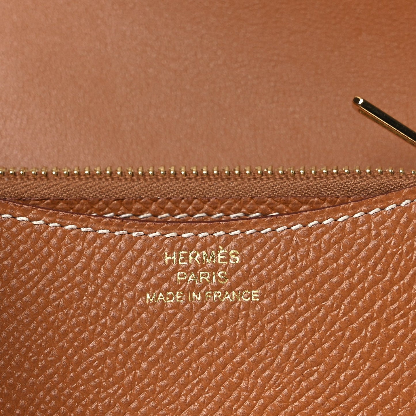 Constance slim wallet close-up showing zipper and embossed marks on tan leather