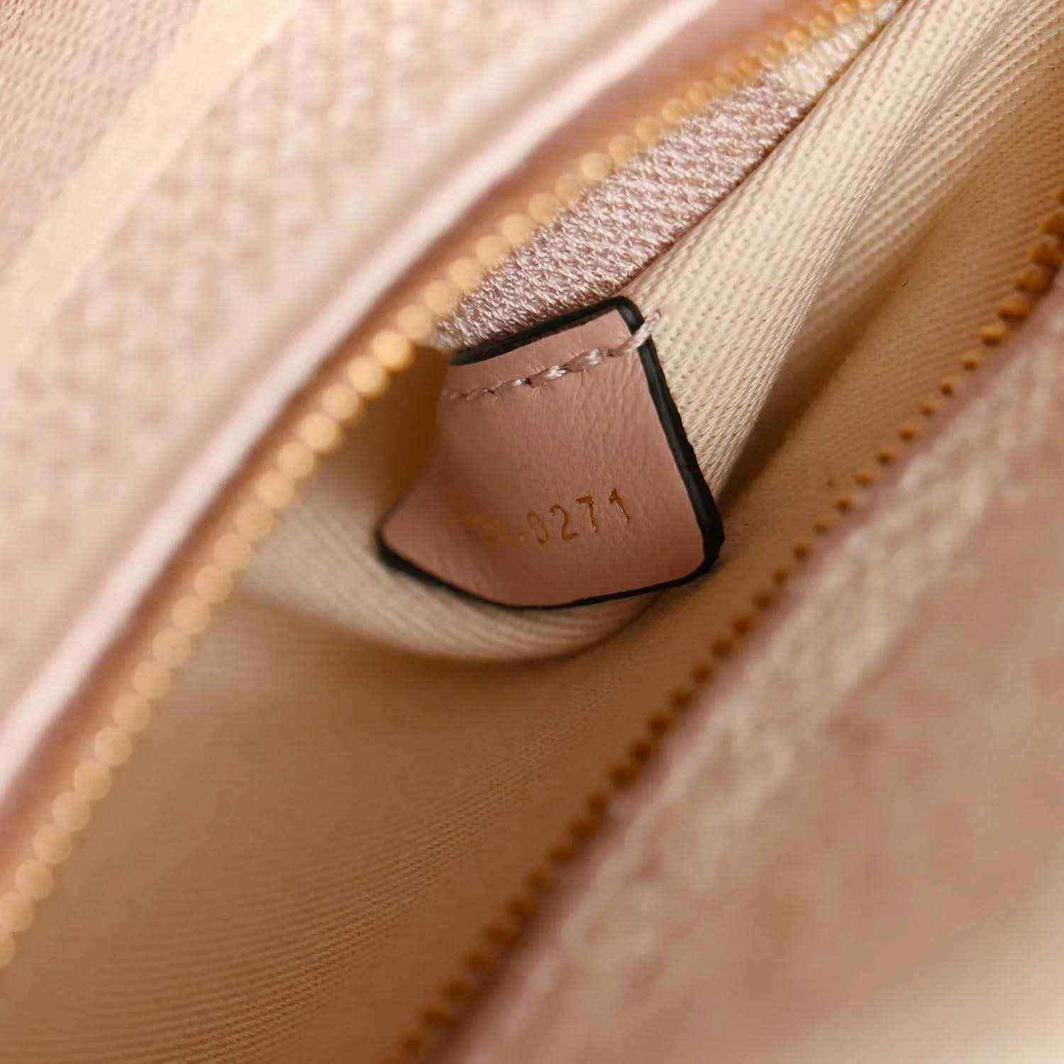 Rose-pink handbag interior seam with stitched pocket edge and zipper pull detail