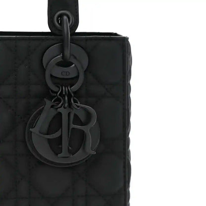 CD charm detail on a black quilted handbag front with ring handle attachment