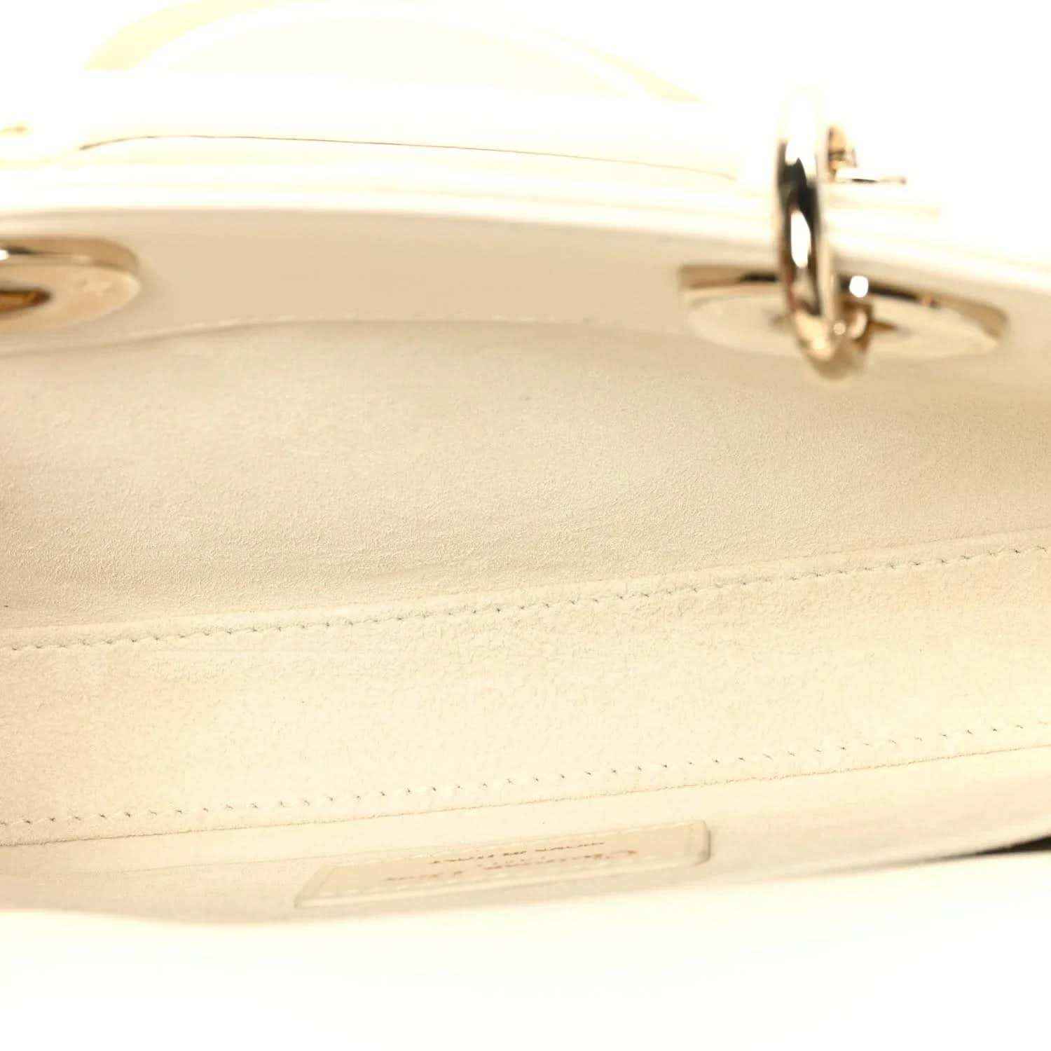 White handbag edge detail with stitched seam and gold-tone clasp hardware